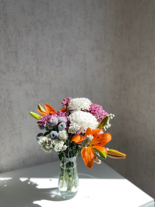  Mixed seasonal bouquet with lily, chrysanthemum, and statice in vase, Bloomin & Buddin signature subscription
